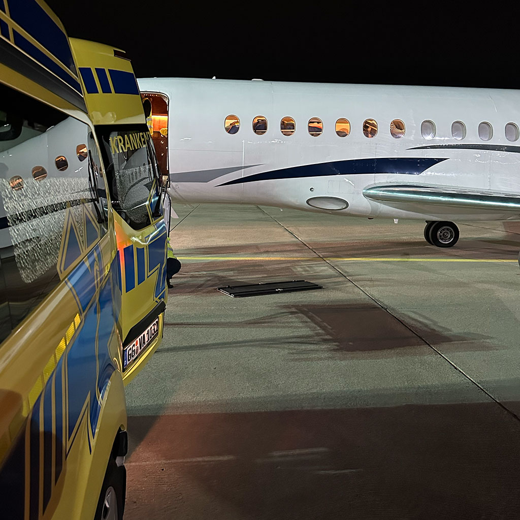 Rettungswagen der Veritas Ambulanz nachts neben einem Ambulanzjet auf dem Vorfeld